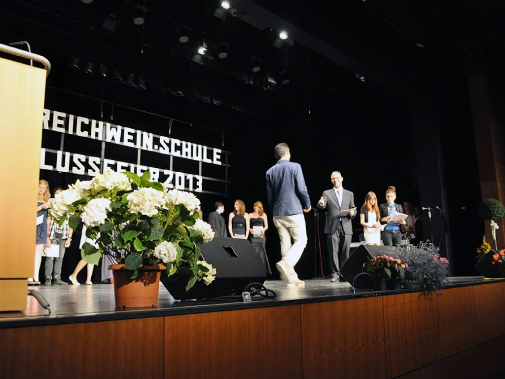 Personen gehen zur Zeugnisübergabe auf die Bühne.